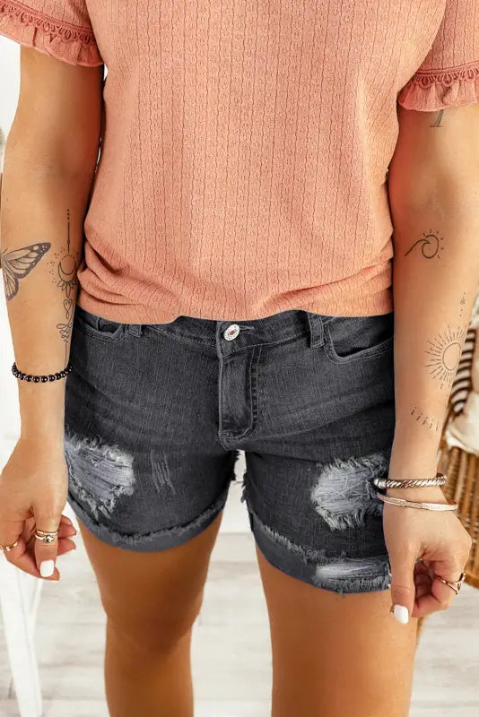 Woman in pink top and distressed ripped denim shorts with tattoos, embrace relax relax style