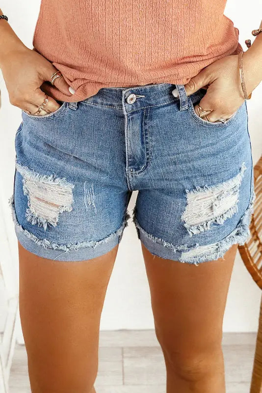 Distressed ripped denim shorts with rolled hem and ripped patches on thighs for a relaxed look