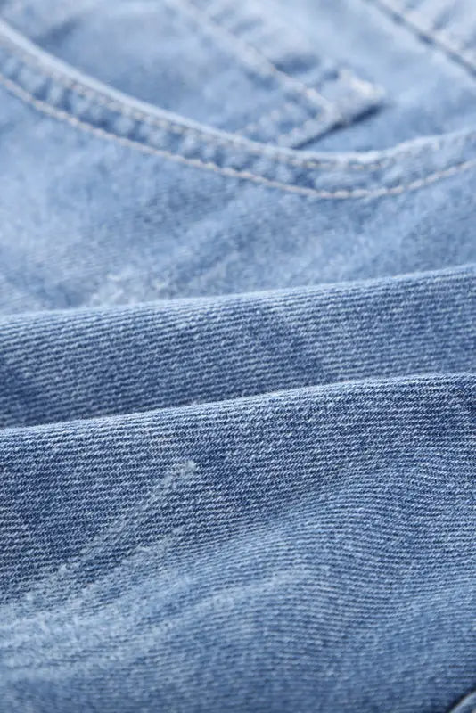 Close-up of distressed ripped denim fabric from distressed ripped denim shorts - rolled hem