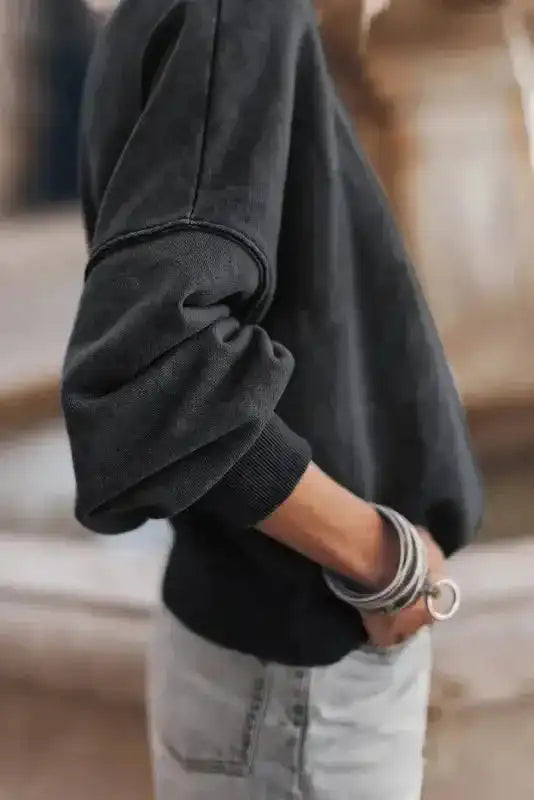 Side view of black Cozy Drop Shoulder Crew Neck Sweatshirt showing drop shoulder seam and ribbed cuff for a laid-back fit.