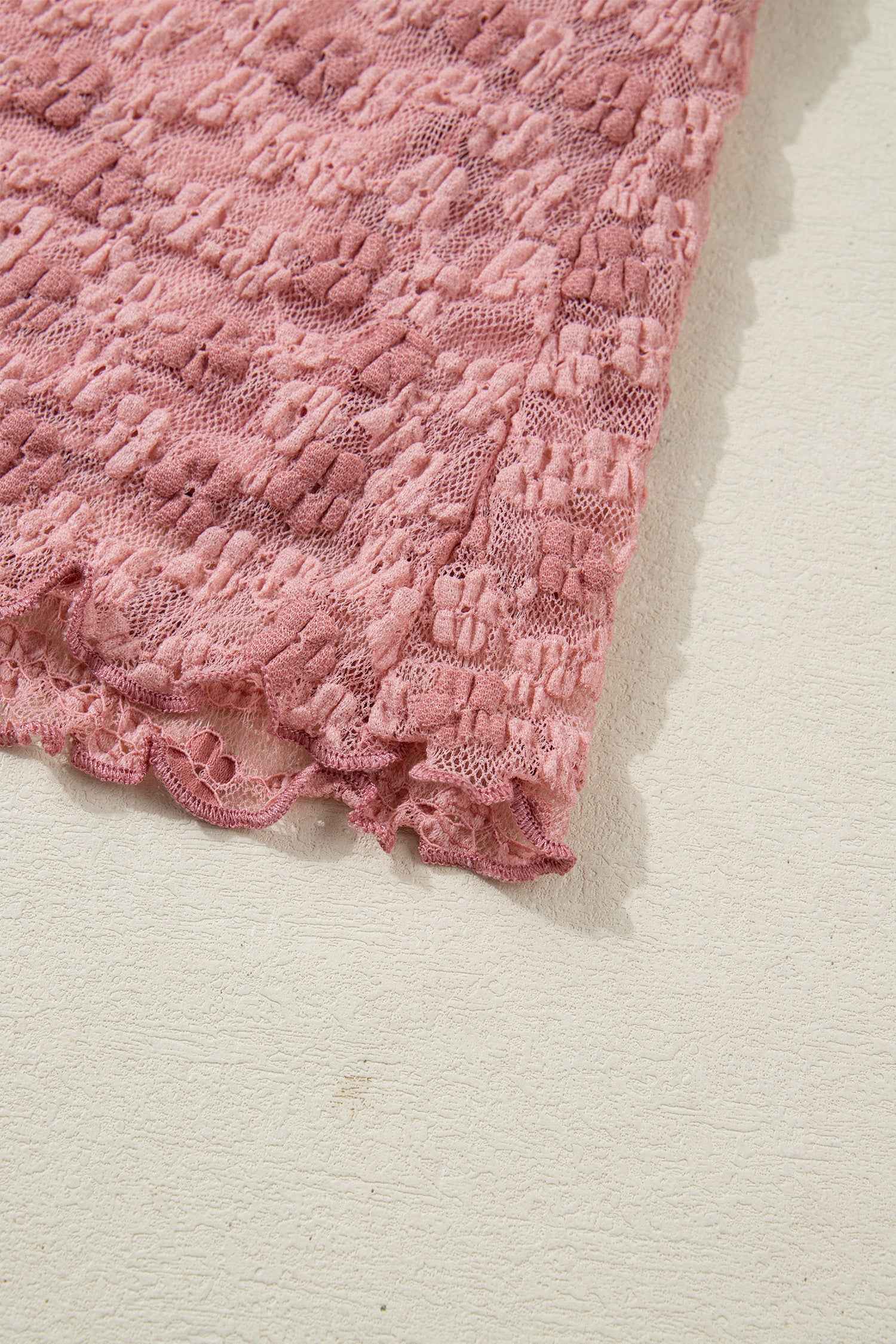 Hem detail of pink floral lace blouse showing scalloped lace edge. Delicate finish enhances romantic and feminine appeal.