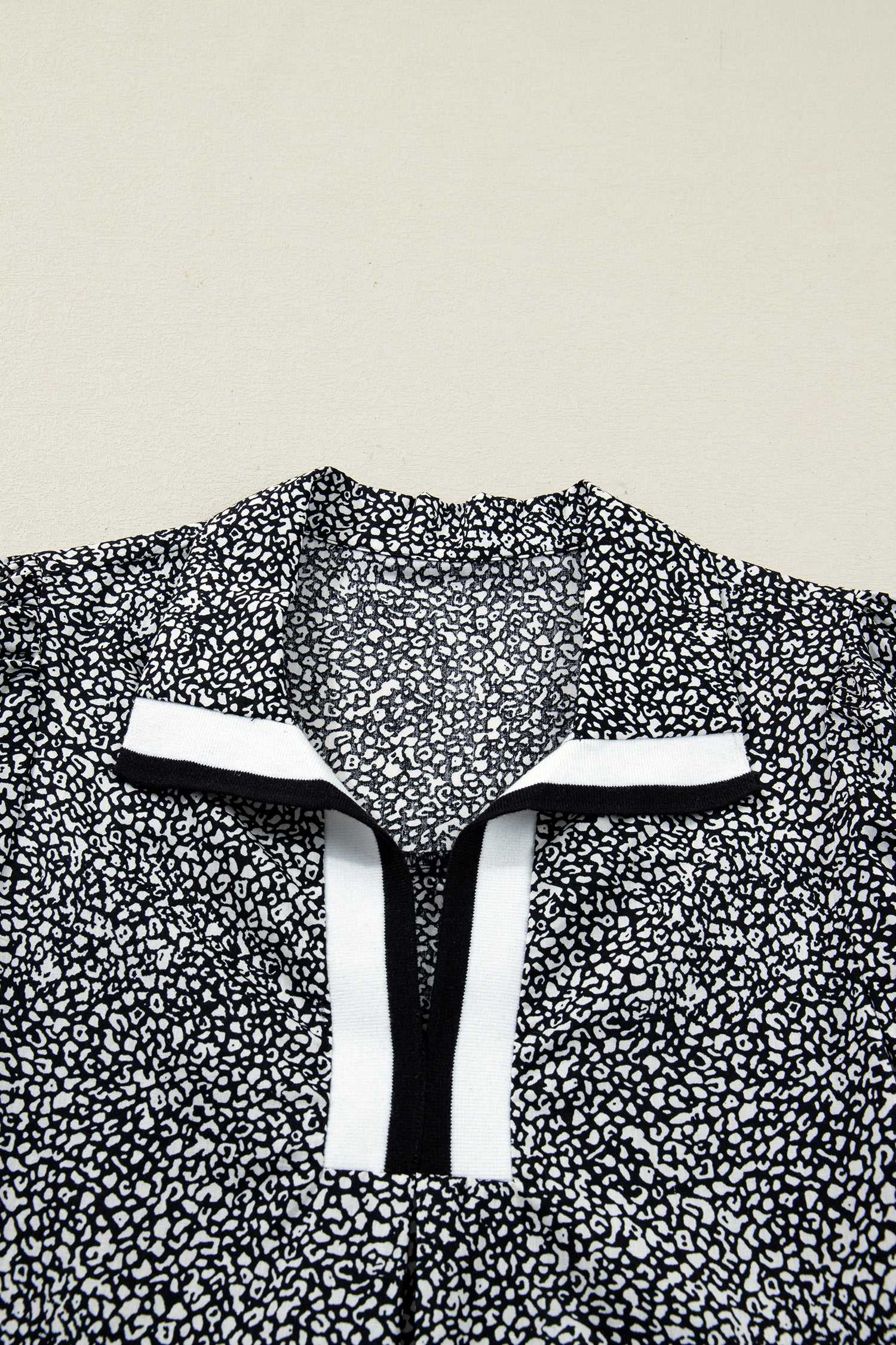 Flat lay of Black Leopard Polo Dress collar highlighting the black and white contrast trim. Bold leopard print adds a modern touch to the neckline.