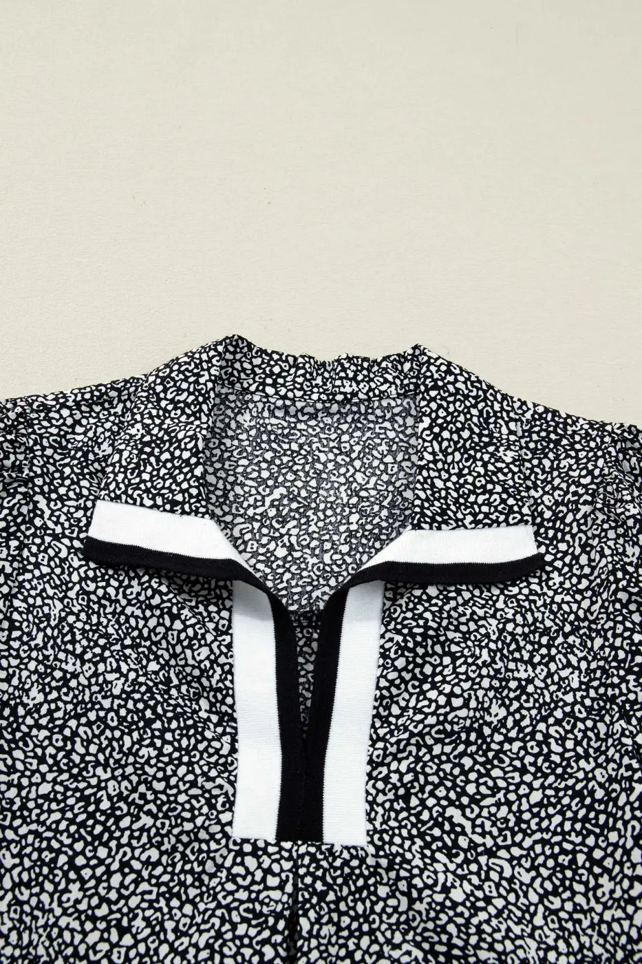 Flat lay of Black Leopard Polo Dress collar highlighting the black and white contrast trim. Bold leopard print adds a modern touch to the neckline.