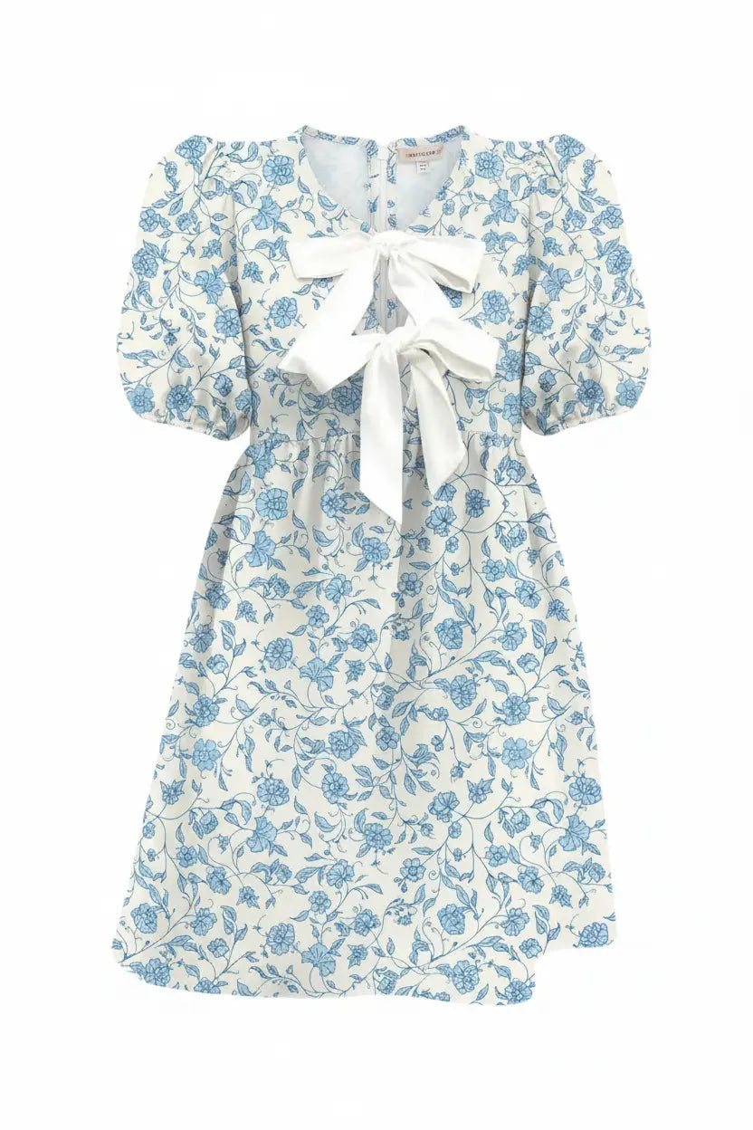 Woman wearing a blue floral dress with a white bow tie on a white background