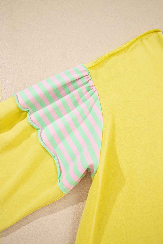 Detail view of striped sleeve on plus size yellow sweatshirt, featuring pink and green stripes with scalloped stitching.