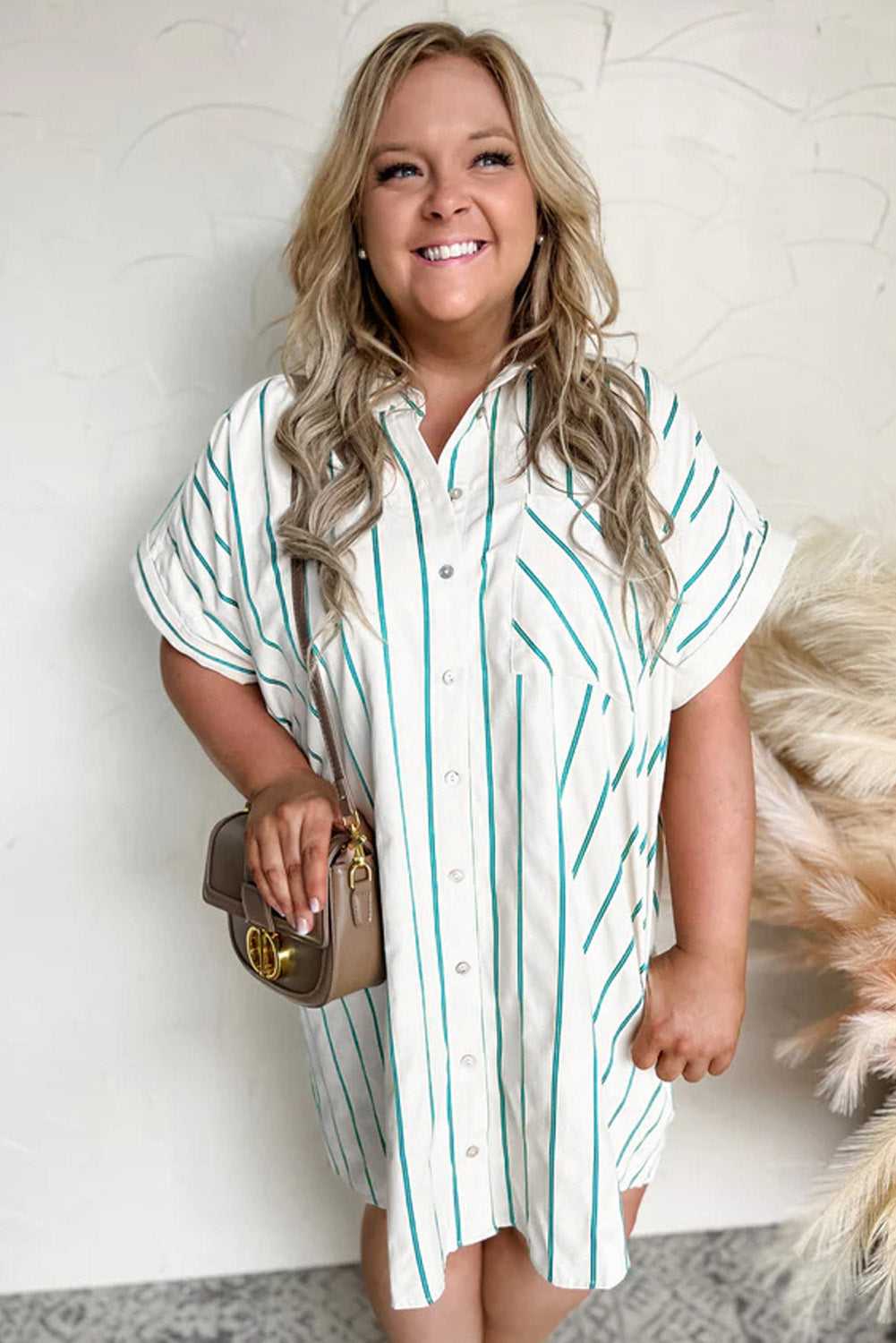 Woman wearing a white and green striped shirt dress against a neutral background