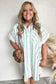 Woman wearing a white and green striped shirt dress against a neutral background