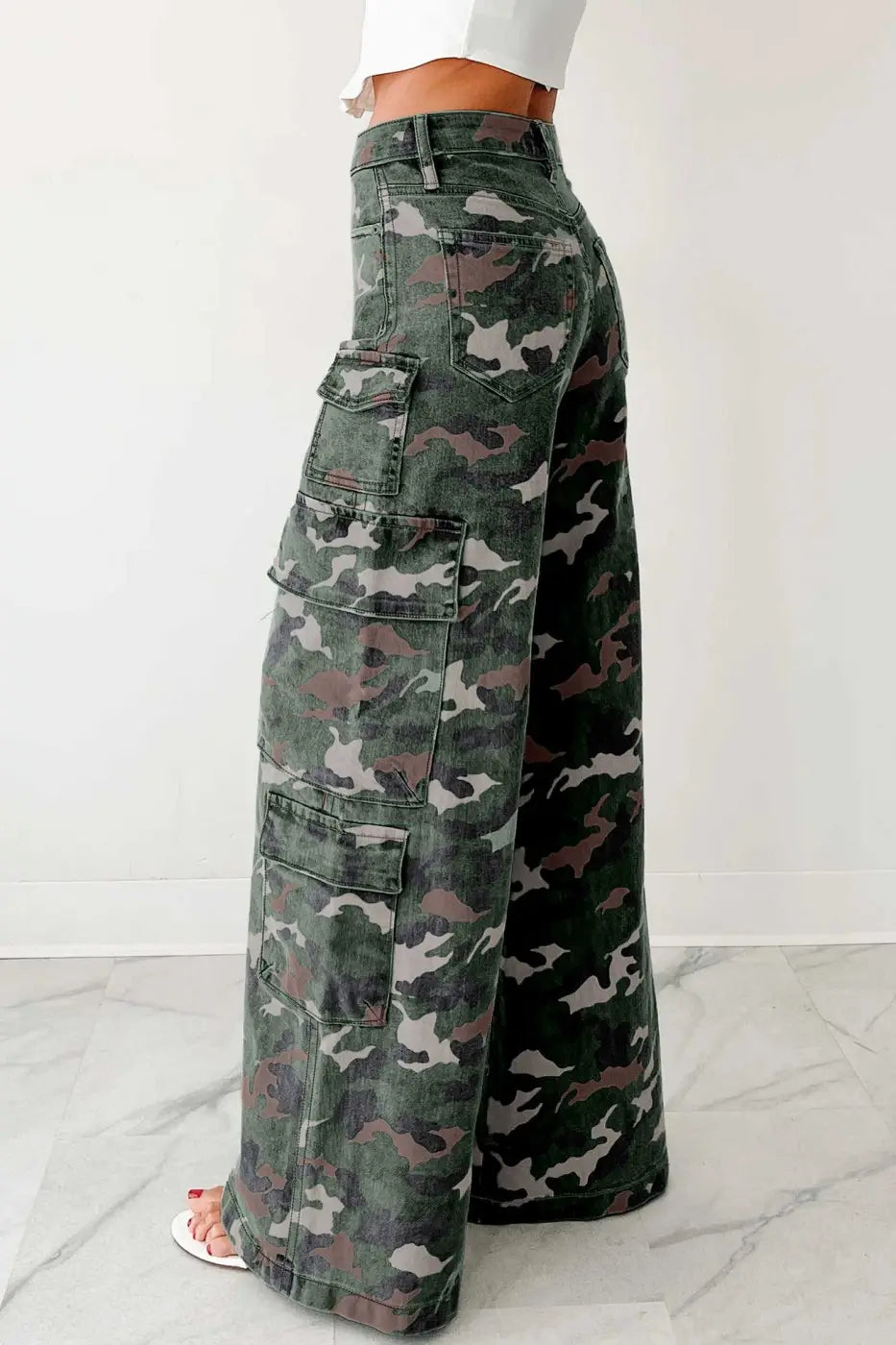 Side view of green camo cargo jeans featuring wide leg silhouette and multiple utility pockets. Stylish high-rise denim for women.