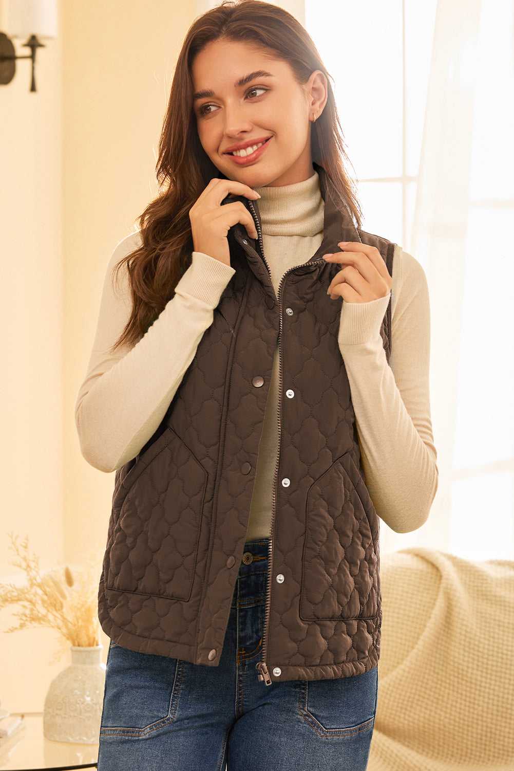 Brown Flower‑Quilted Winter Gilet styled indoors with turtleneck and jeans, showcasing zip and snap-button closure for warm winter layering.