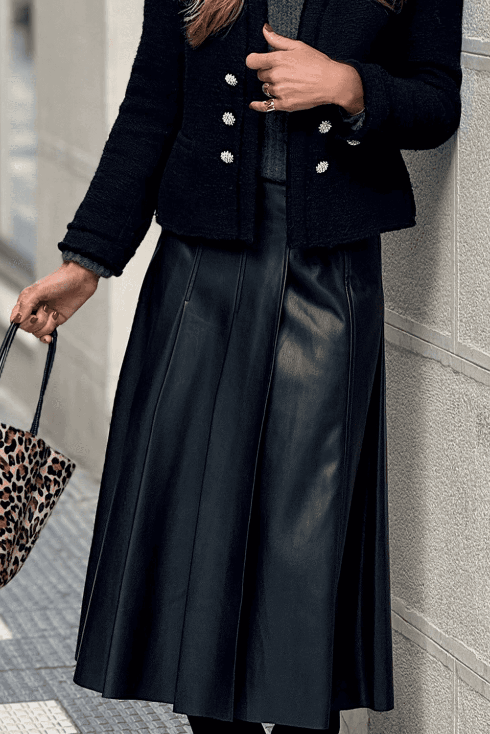 Black Faux Leather Pleated Flared Skirt | FashionFitz styled with black jacket and green top, showing elegant pleats and mid-length cut.