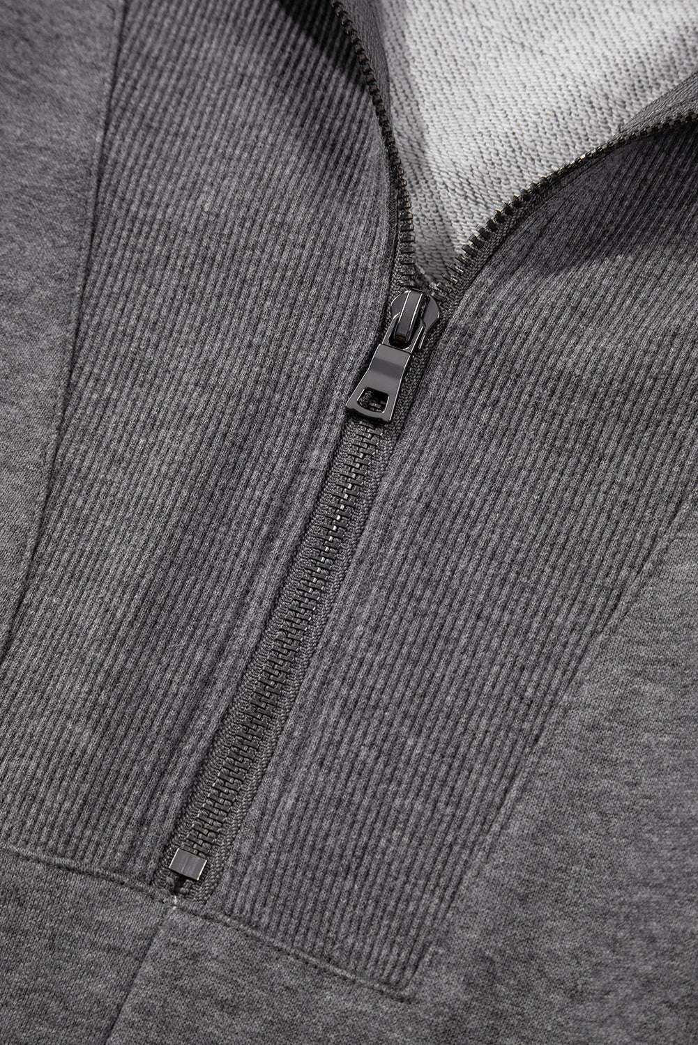 Close-up of gray zip-up sweatshirt dress zipper and ribbed collar, showcasing quality stitching and casual design.