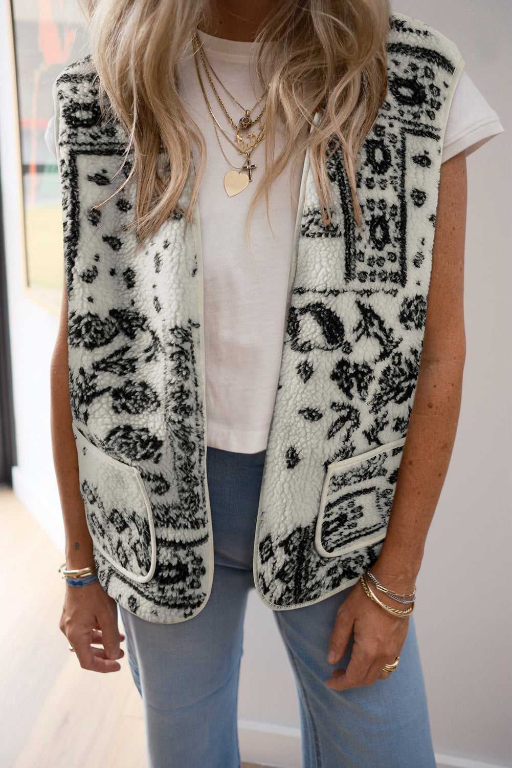 Woman wearing Paisley Sherpa Gilet – Beige Western Style Vest layered over a white tee with blue jeans, showcasing casual autumn fashion.
