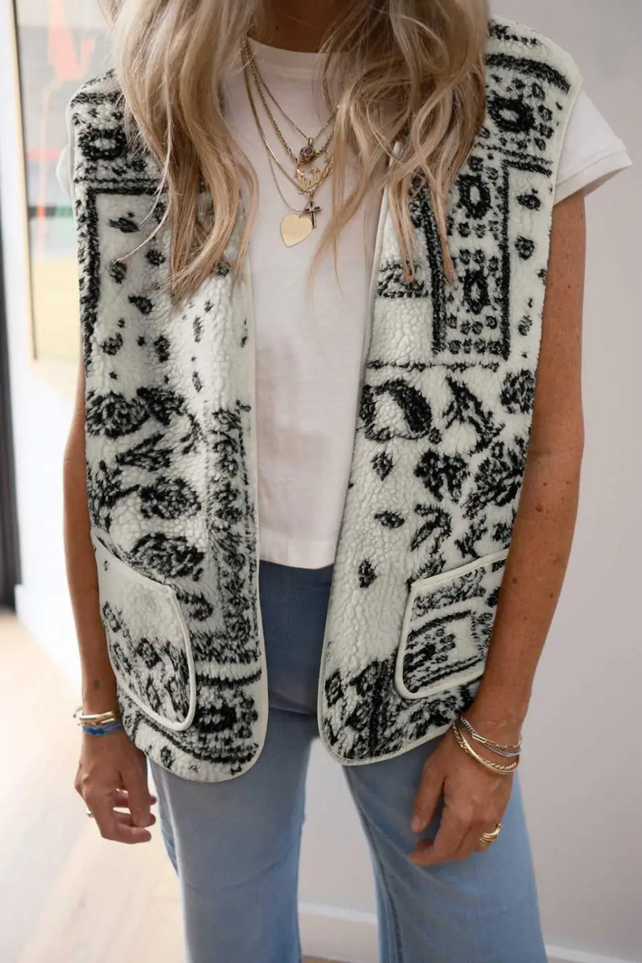 Woman wearing Paisley Sherpa Gilet – Beige Western Style Vest layered over a white tee with blue jeans, showcasing casual autumn fashion.