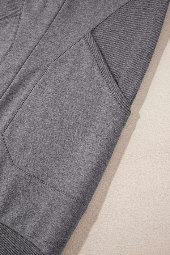 Detail of side pocket and sleeve ribbing on gray sweatshirt mini dress, emphasizing comfort and practical style.