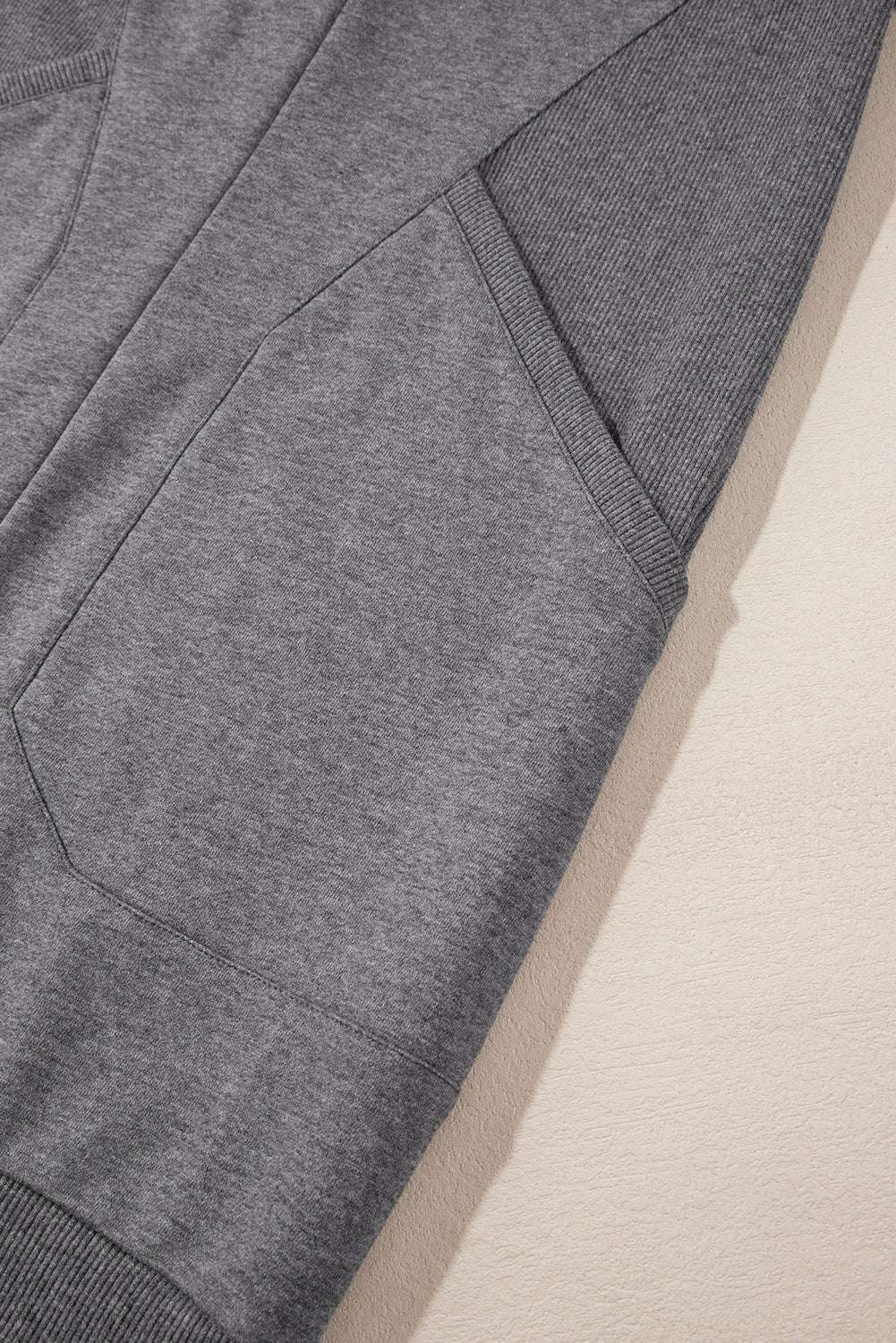 Detail of side pocket and sleeve ribbing on gray sweatshirt mini dress, emphasizing comfort and practical style.