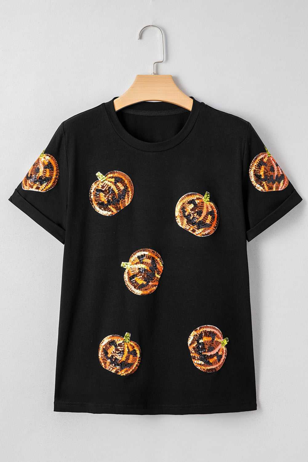 Sequin Pumpkin Face Halloween T-Shirt on a hanger against a gray background