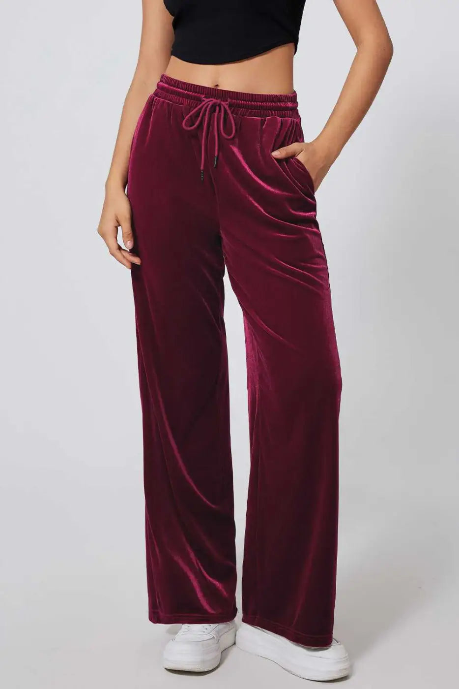 Burgundy velvet drawstring trousers with wide-leg silhouette, styled with a black crop top and white sneakers for casual activewear.