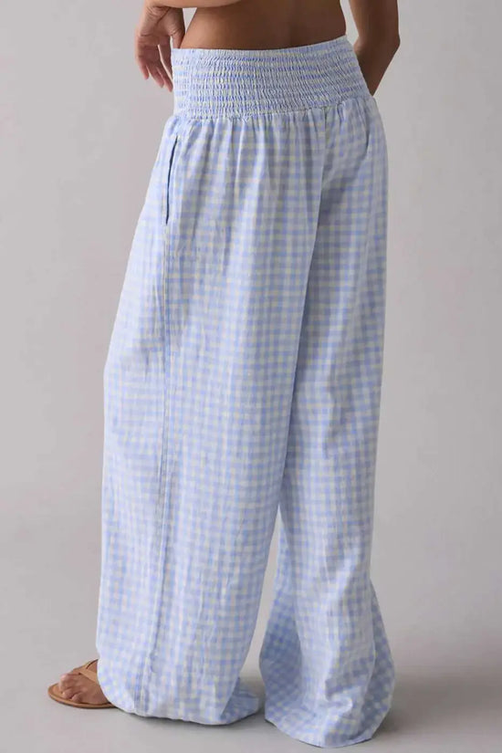 back view of Model wearing plaid wide-leg trousers with elastic waist and relaxed fit