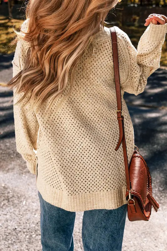 Eyelet elegance drop: cream-colored chunky knit sweater with jeans and a brown leather bag