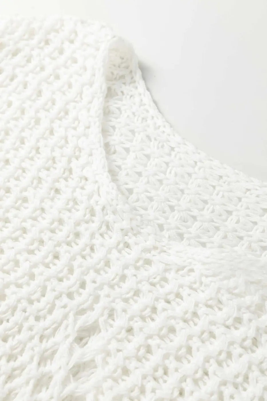Detailed close-up of white wide sleeve hollow knit jumper neckline and texture, emphasizing its soft, breathable knit fabric.