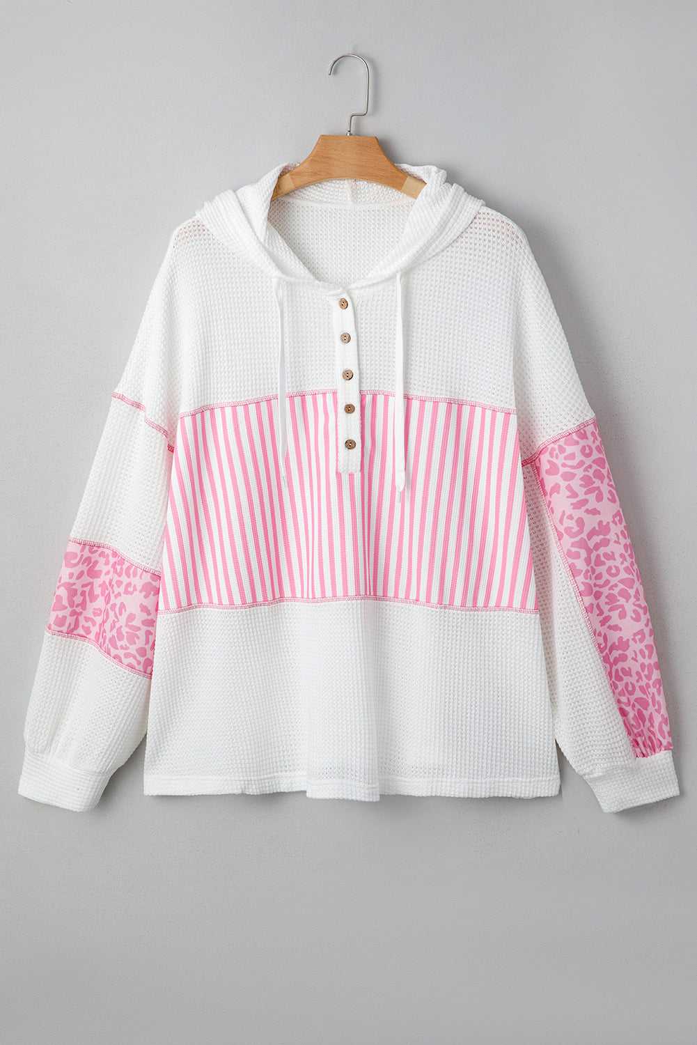 Flat lay of Curve Pink Leopard Stripe Waffle Hoodie for Women on hanger, displaying pink stripe and leopard patchwork on white waffle knit fabric.