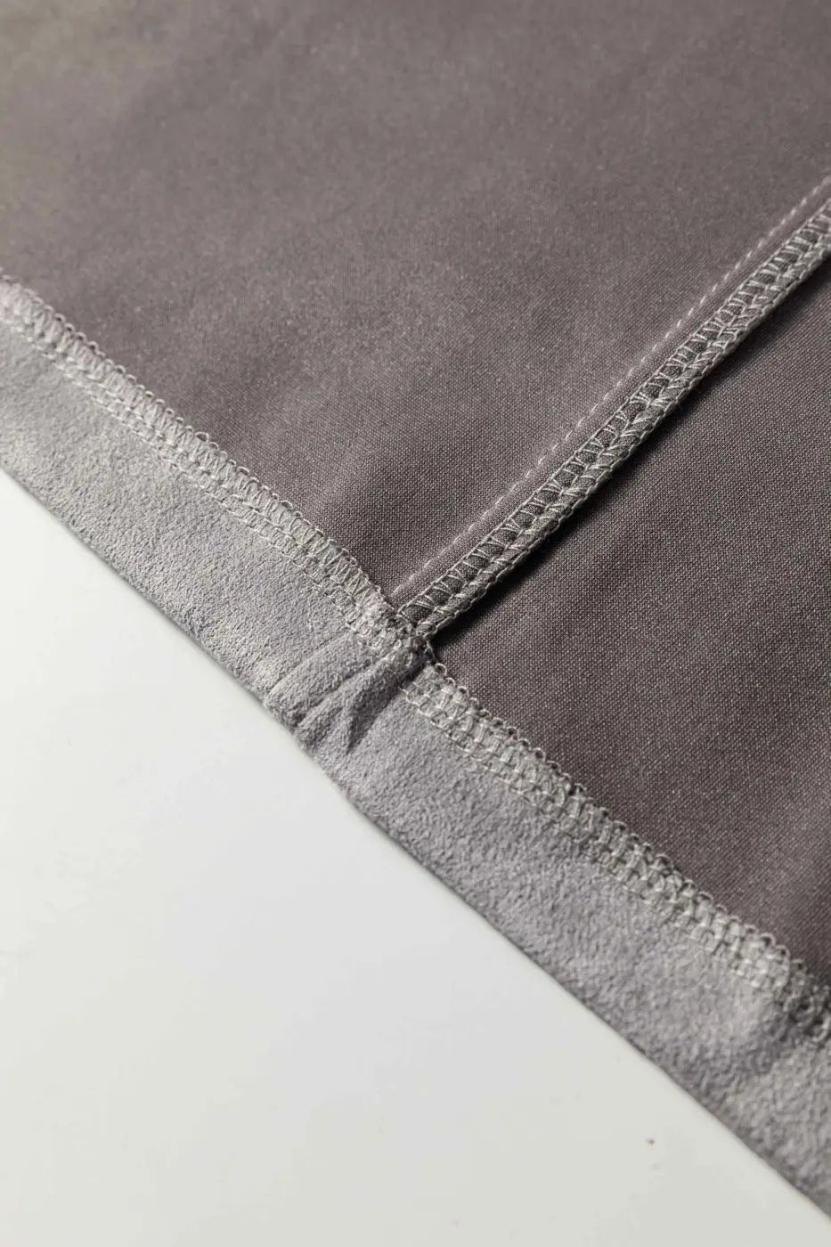 Close-up of inner seam stitching on gray faux suede jacket, emphasizing quality craftsmanship and soft fabric texture.