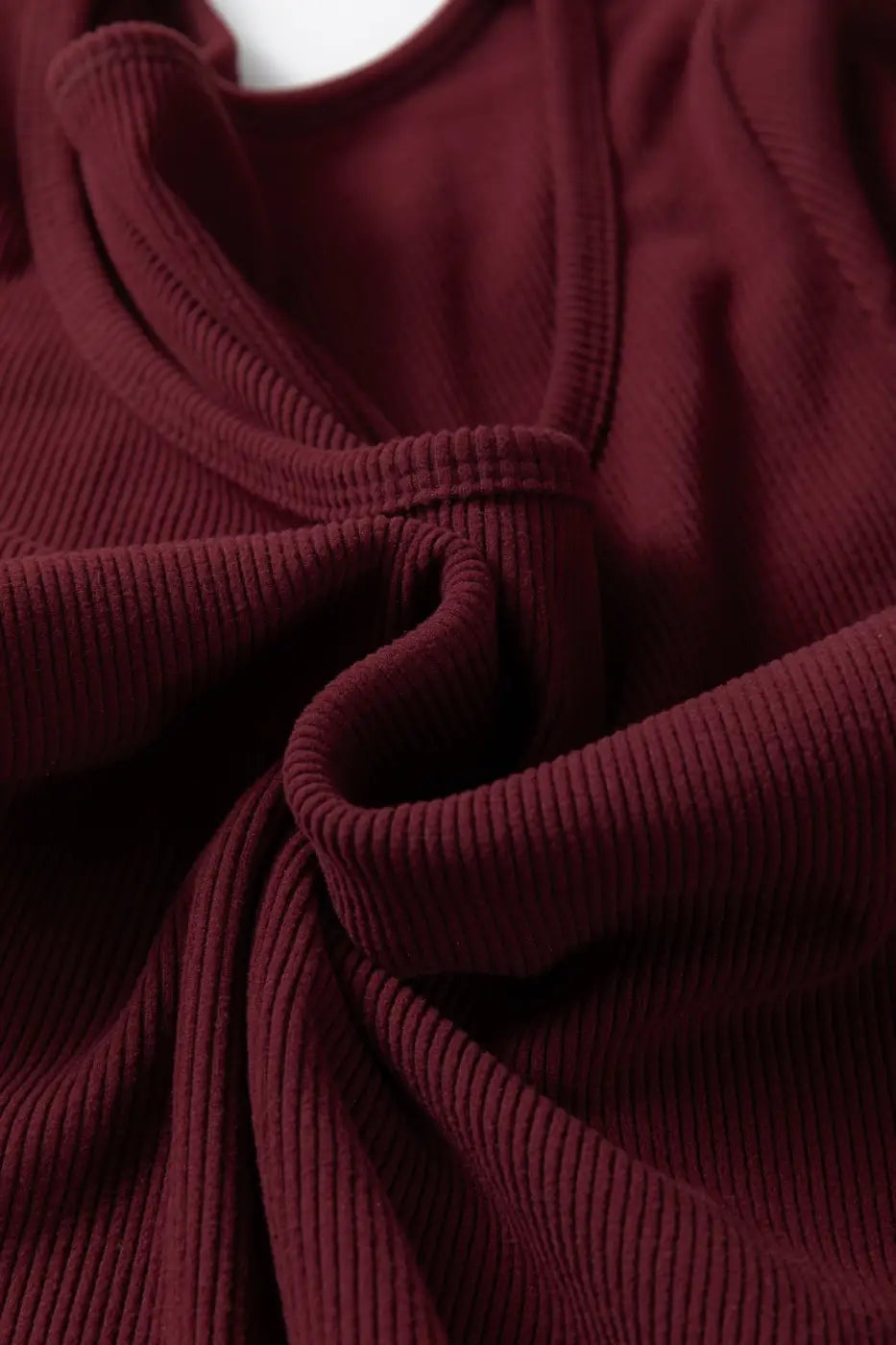 Detail of brown ribbed long sleeve crop top fabric twisted to show soft stretch knit. Ideal for casual and layering wear.