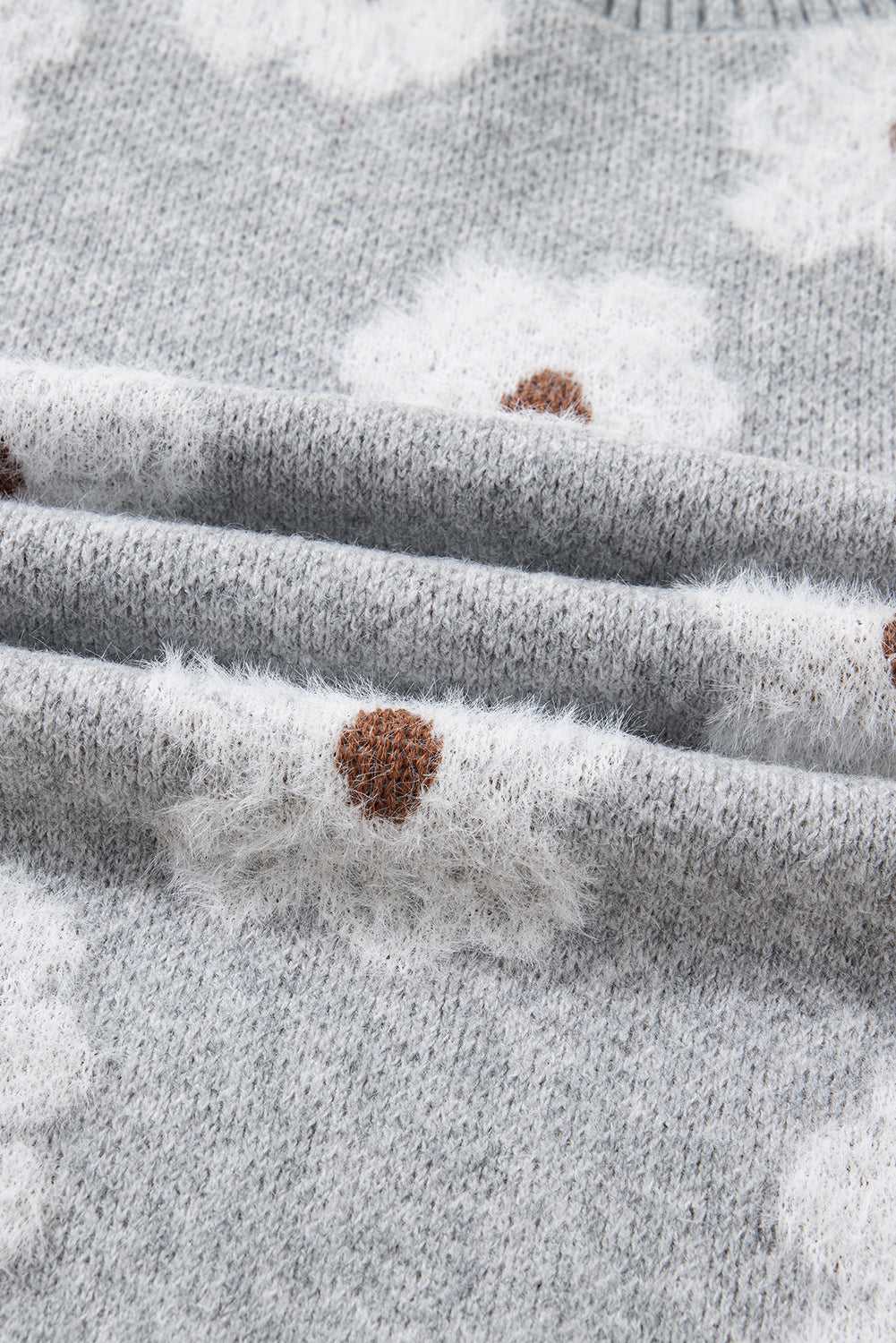 Folded fabric detail of FashionFitz Oversized Grey Floral Knit Jumper showing soft knit texture and white floral pattern with brown centers.