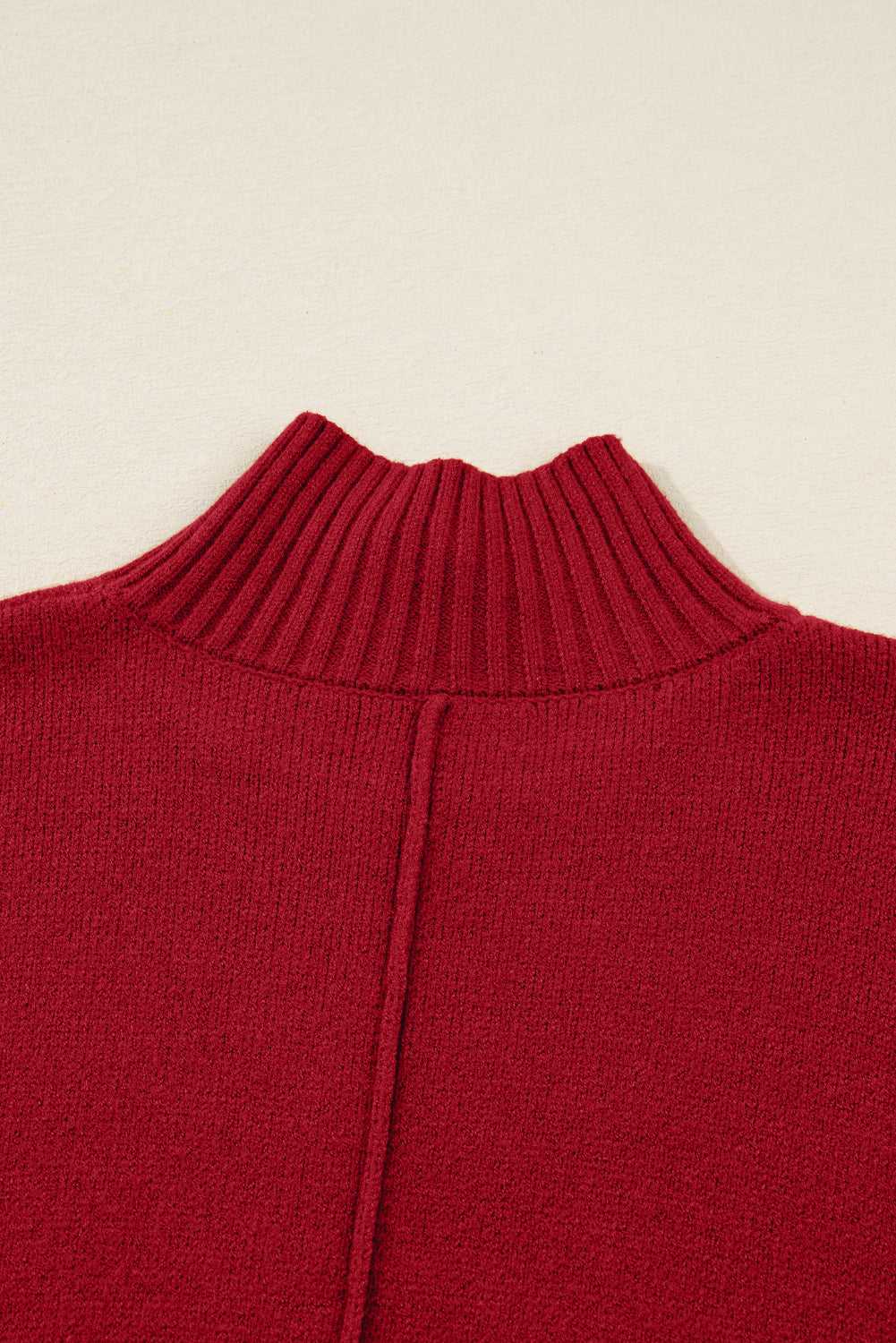 Close-up of ribbed high neckline on red knit jumper dress. Fine knit texture ideal for cozy winter wear in women’s sweater dresses.