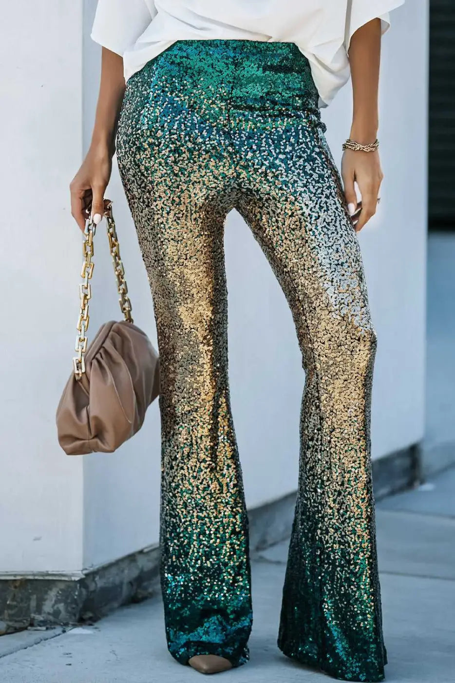 Front close-up of green and gold gradient sequin flared trousers for women. Glamorous party pants with flattering flare cut.