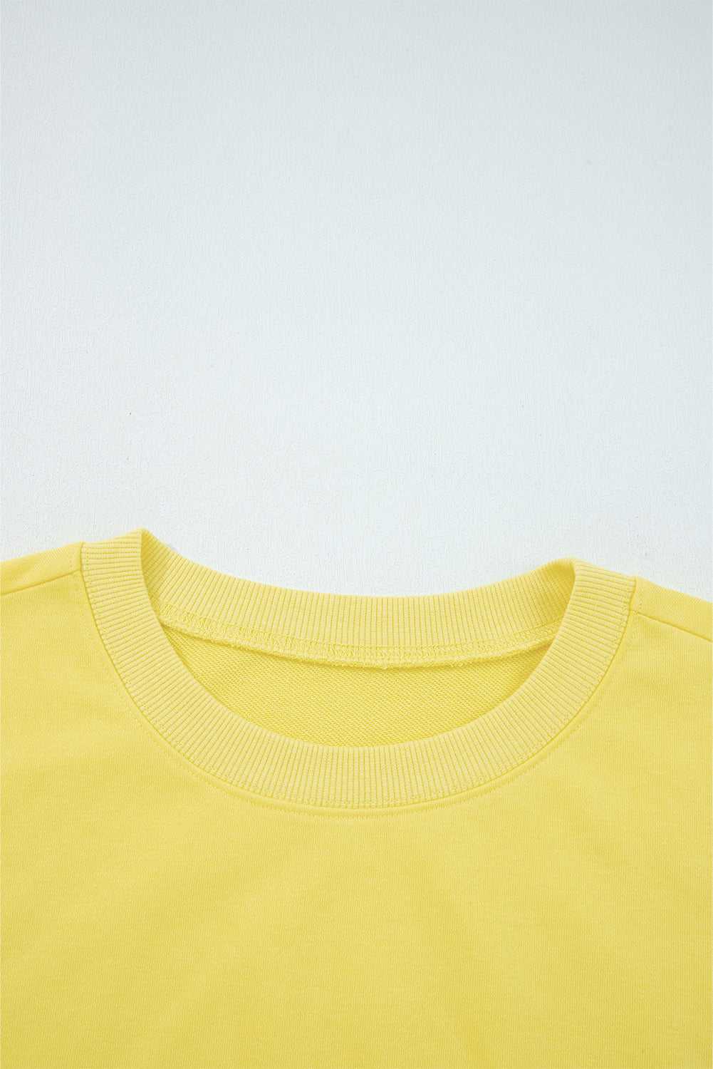 Close-up of yellow Drop Crop Set neckline with ribbed trim, highlighting quality construction and comfort-focused design.