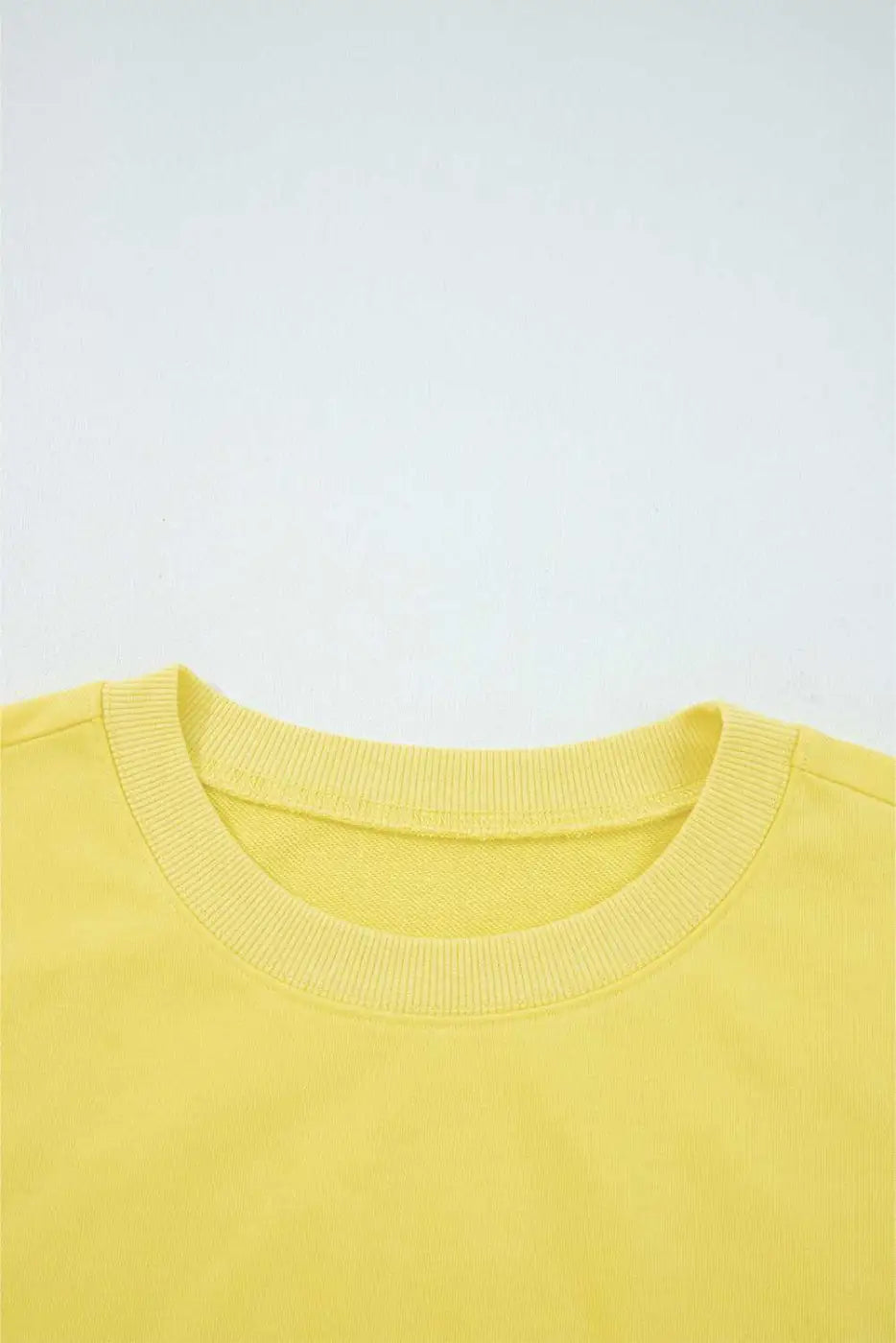 Close-up of yellow Drop Crop Set neckline with ribbed trim, highlighting quality construction and comfort-focused design.