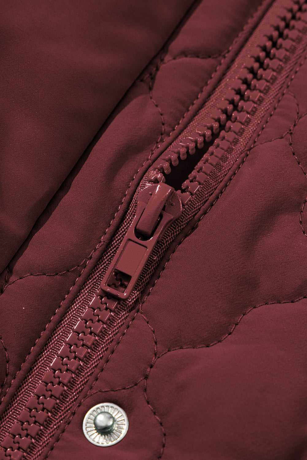 Close-up of zipper and snap button on burgundy Flower‑Quilted Winter Gilet, emphasizing secure closure and quality craftsmanship in winter vests.