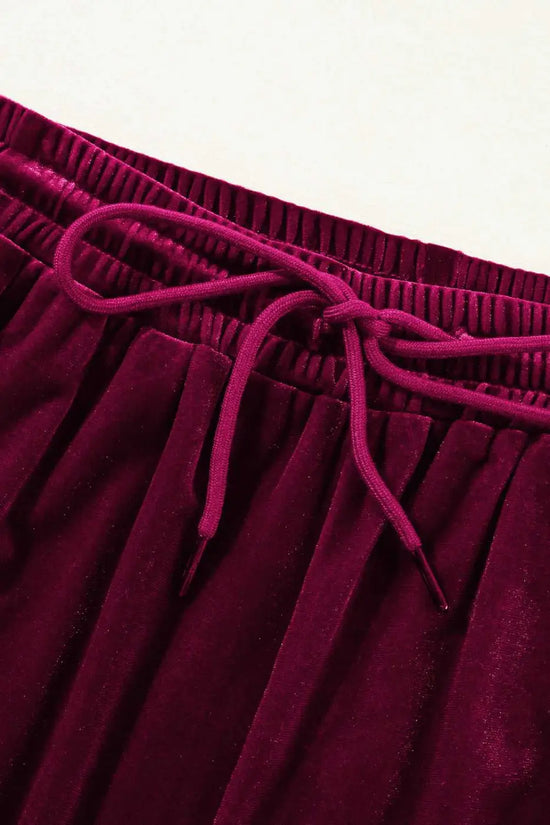 Close-up of drawstring waistband on burgundy velvet trousers, highlighting soft fabric and adjustable fit for activewear comfort.