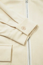 Close-up of a beige corduroy jacket with a zipper and button detail.