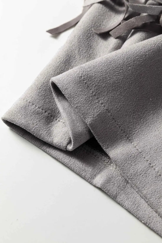 Detailed view of sleeve hem on gray cropped fringe faux suede jacket, showing fine stitching and suede material.
