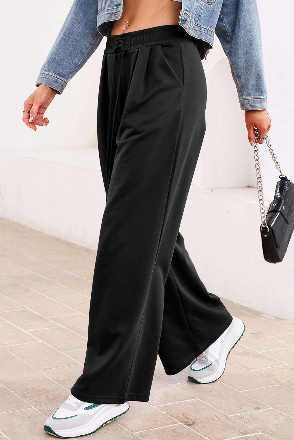 Side view of black pleated sweatpants with drawstring waist, styled for a sporty yet fashionable fall outfit.