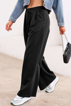 Side view of black pleated sweatpants with drawstring waist, styled for a sporty yet fashionable fall outfit.