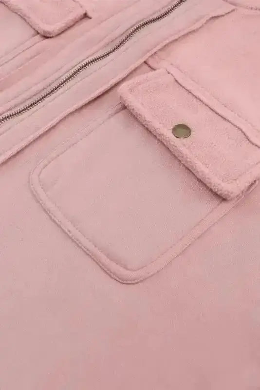 Close-up of flap pocket and zipper on pink women's zip up hooded jacket. Functional and stylish outerwear for casual cold-weather looks.