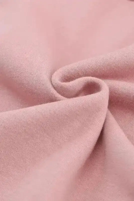 Close-up of soft pink fleece fabric used in women's zip up hooded jacket. High-stretch material for cozy and comfortable fit.