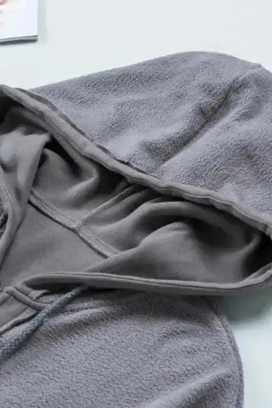 Detail of gray fleece hood with inner stitching on women's zip up hooded jacket. Cozy drawstring coat for casual cold-weather outfits.