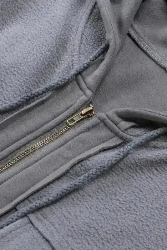 Close-up of gray zip up hooded jacket for women with fleece lining and metal zipper. Casual drawstring coat ideal for fall and winter wear.