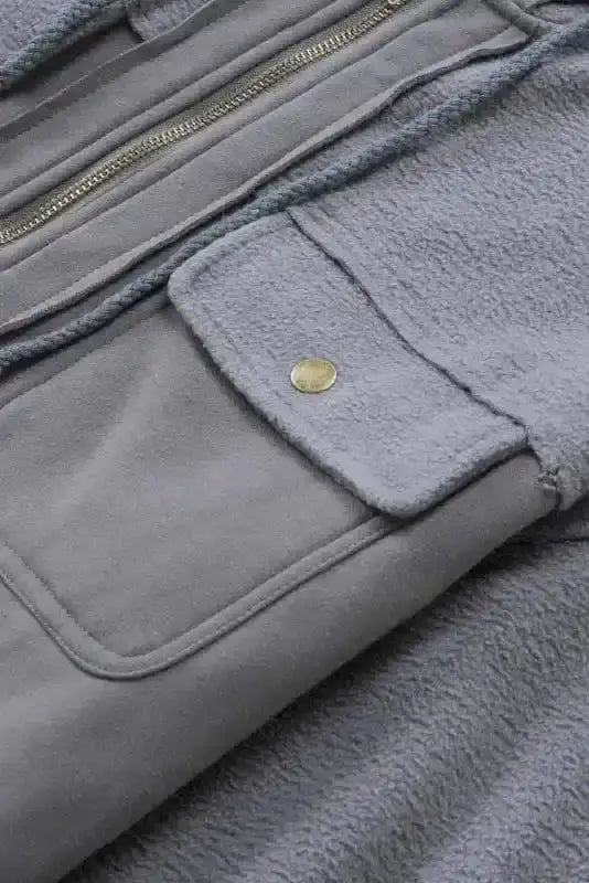 Flap pocket with snap button on gray zip up hooded jacket for women, emphasizing functional and stylish design.