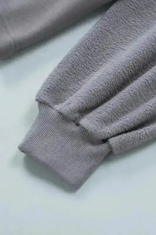 Ribbed cuff detail on gray women's hooded jacket, showcasing cozy fleece sleeve for fall and winter comfort.