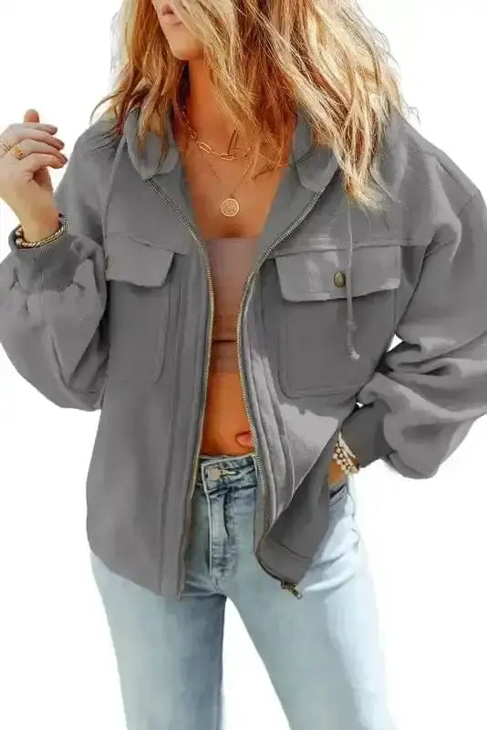 Gray zip up hooded jacket for women styled with light denim, featuring functional flap pockets and fleece lining.