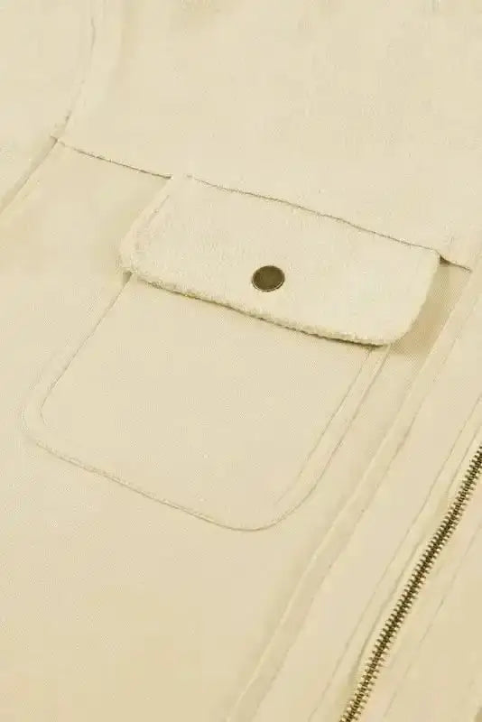 Close-up of flap pocket with button on beige zip up hooded jacket women. Functional design for casual outerwear.