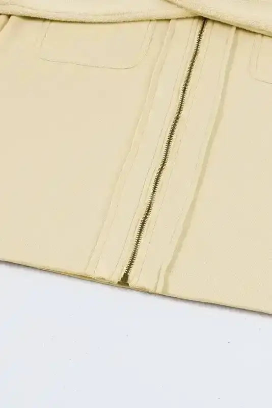 Bottom hem close-up of beige zip up hooded jacket women. Clean stitching and smooth zipper design.