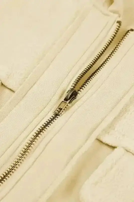 Detail of metal zipper on beige zip up hooded jacket women. Durable closure on cozy fleece outerwear.