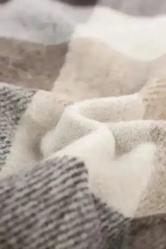 Macro shot of soft plaid fabric in beige and gray tones, emphasizing cozy texture ideal for fall and winter layering.