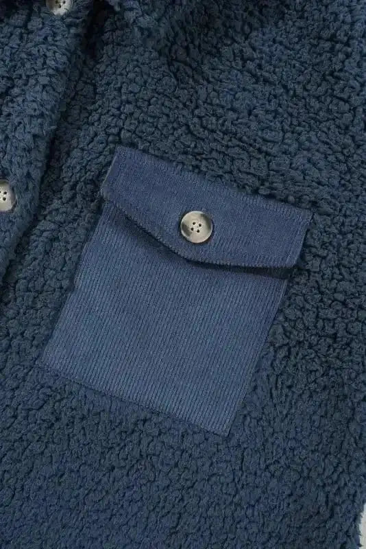 Close-up of blue teddy coat's corduroy pocket with button detail, showcasing stylish contrast and functional winter design.